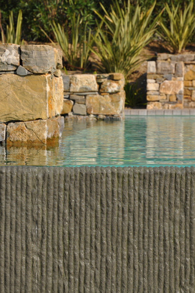 Modelo de casa de la piscina y piscina elevada contemporánea de tamaño medio rectangular en patio trasero con adoquines de piedra natural