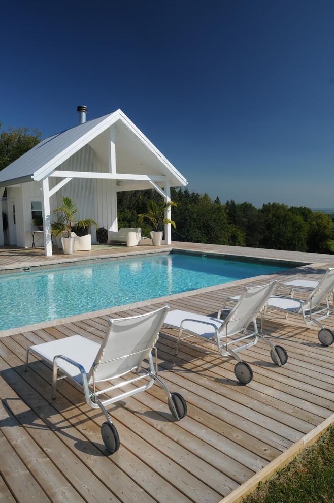 Imagen de casa de la piscina y piscina moderna grande en forma de L en patio trasero con entablado