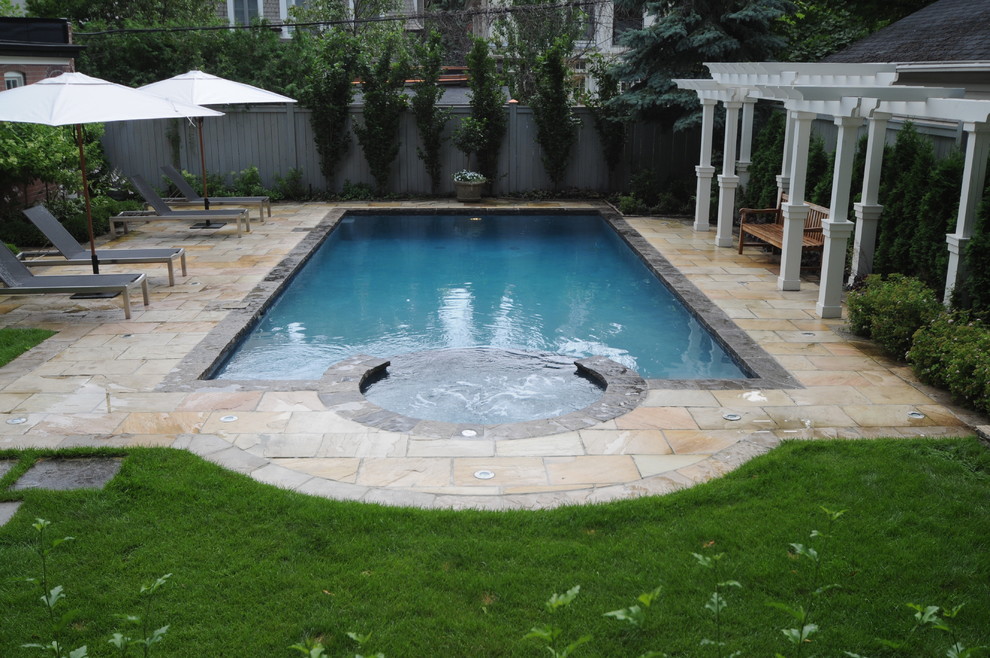 Example of a mid-sized classic backyard stone and rectangular pool fountain design in Toronto