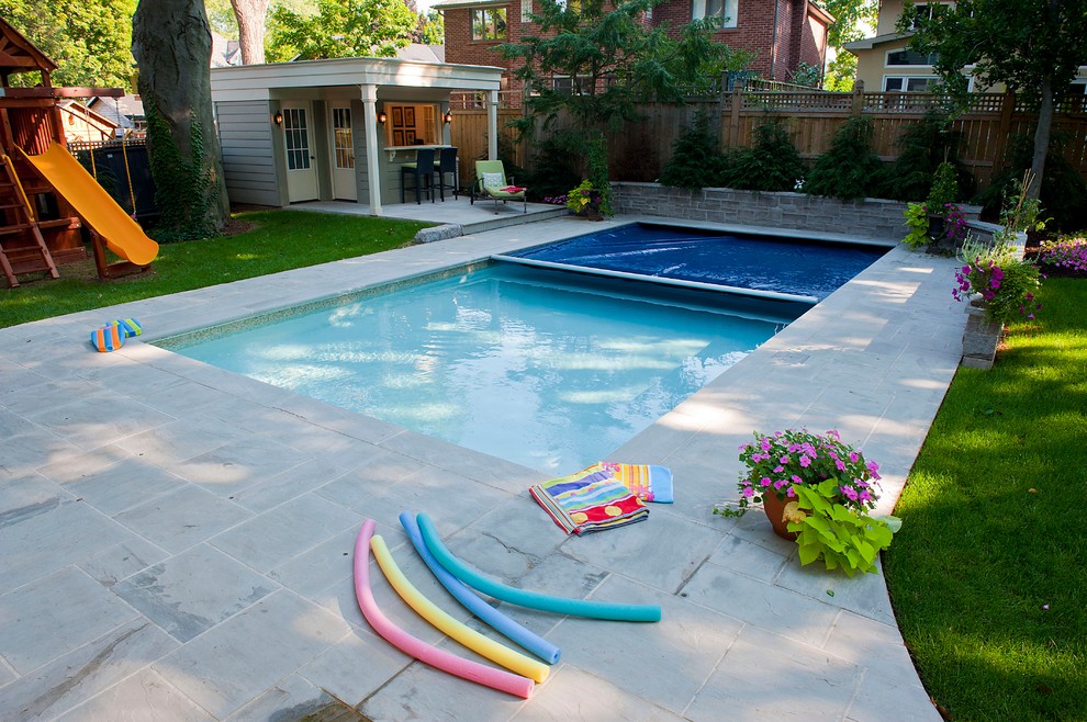 Idée de décoration pour une grande piscine arrière tradition avec des pavés en pierre naturelle.
