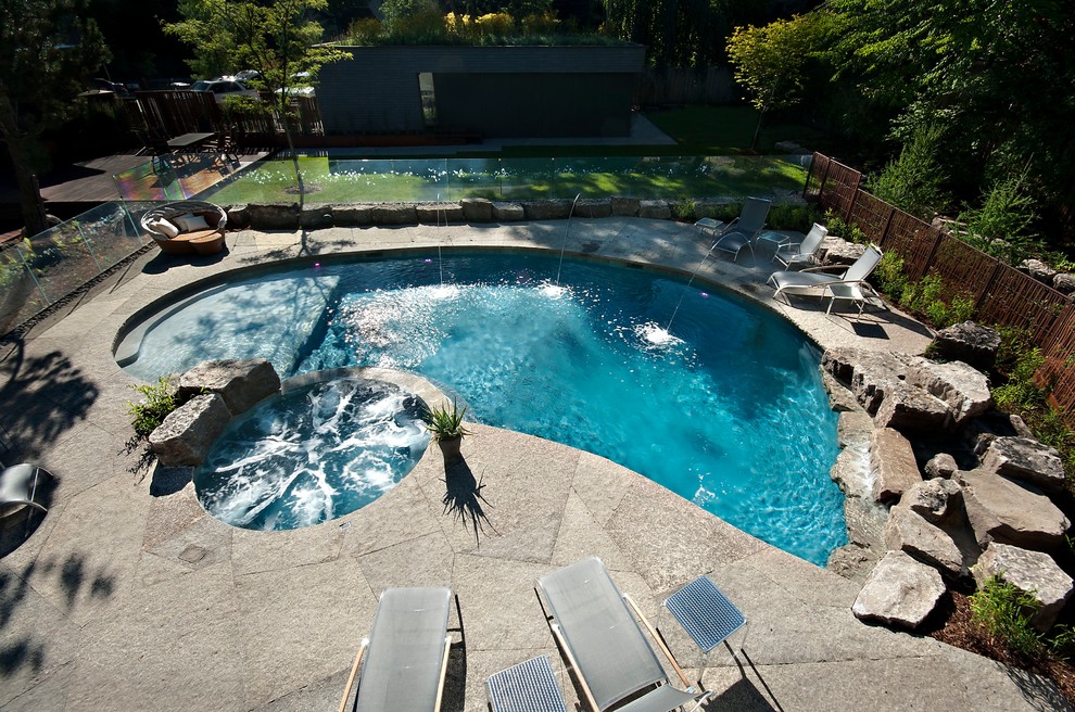 Modelo de piscinas y jacuzzis clásicos de tamaño medio a medida en patio trasero con adoquines de piedra natural