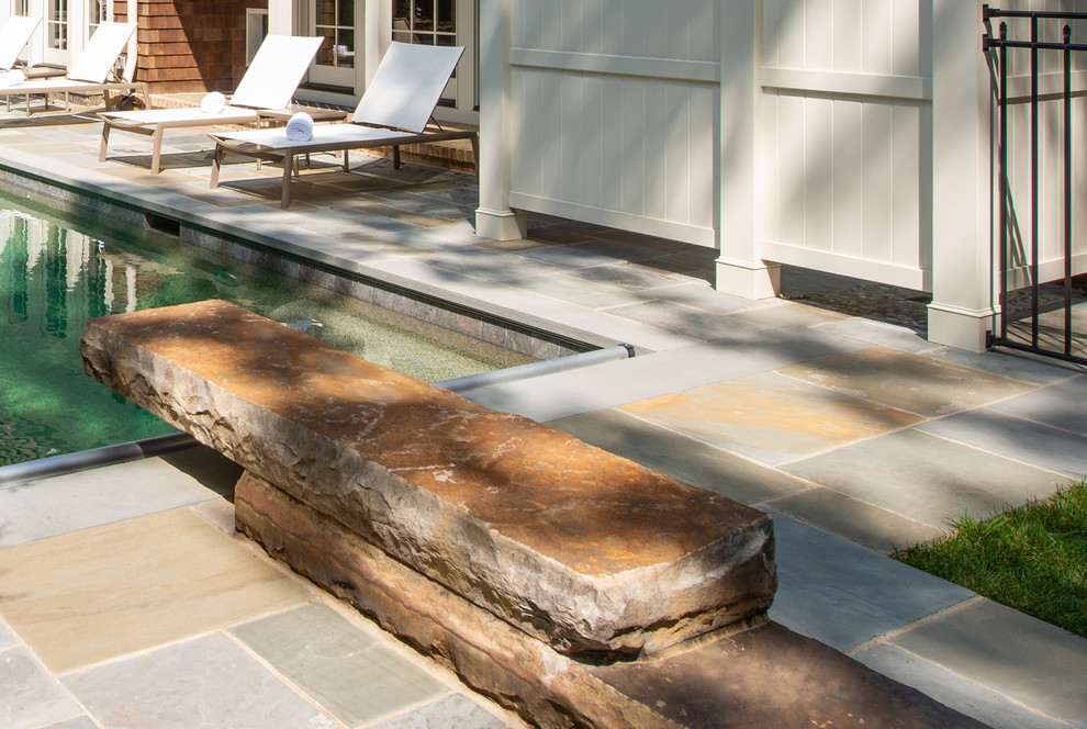 Réalisation d'une grande piscine naturelle et arrière marine rectangle avec un point d'eau et des pavés en pierre naturelle.