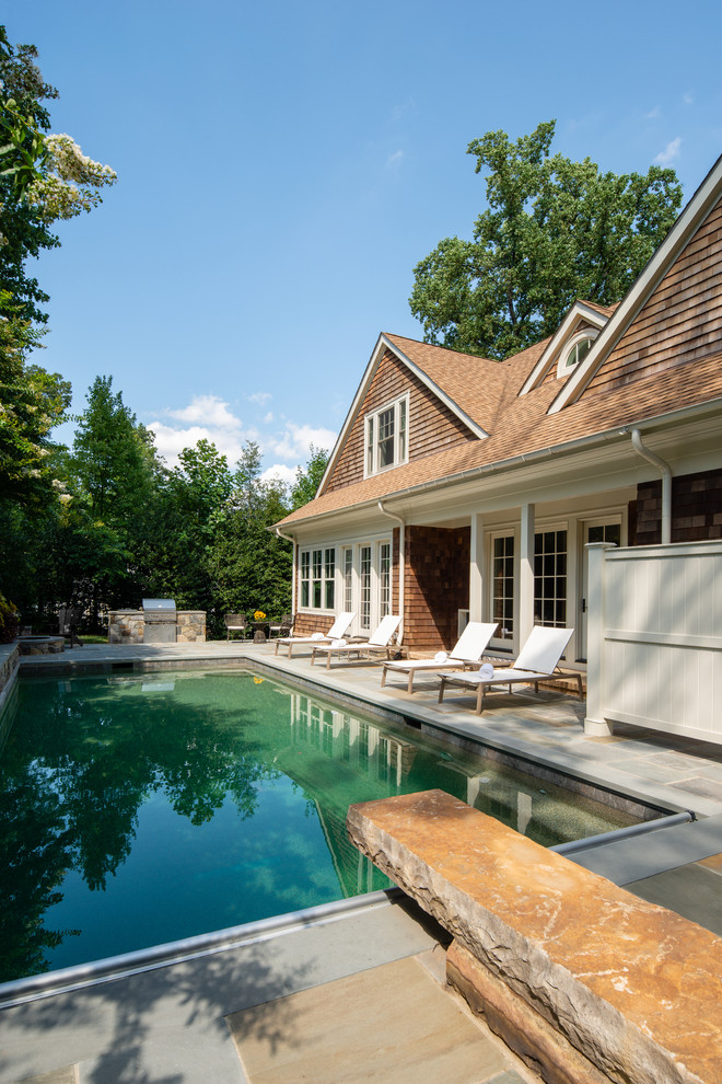 Esempio di una grande piscina naturale stile marino rettangolare dietro casa con fontane e pavimentazioni in pietra naturale