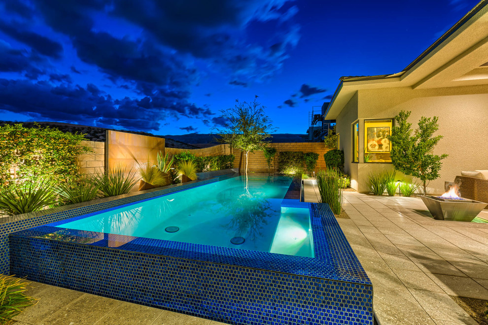 Imagen de piscina infinita contemporánea de tamaño medio rectangular en patio trasero con adoquines de hormigón
