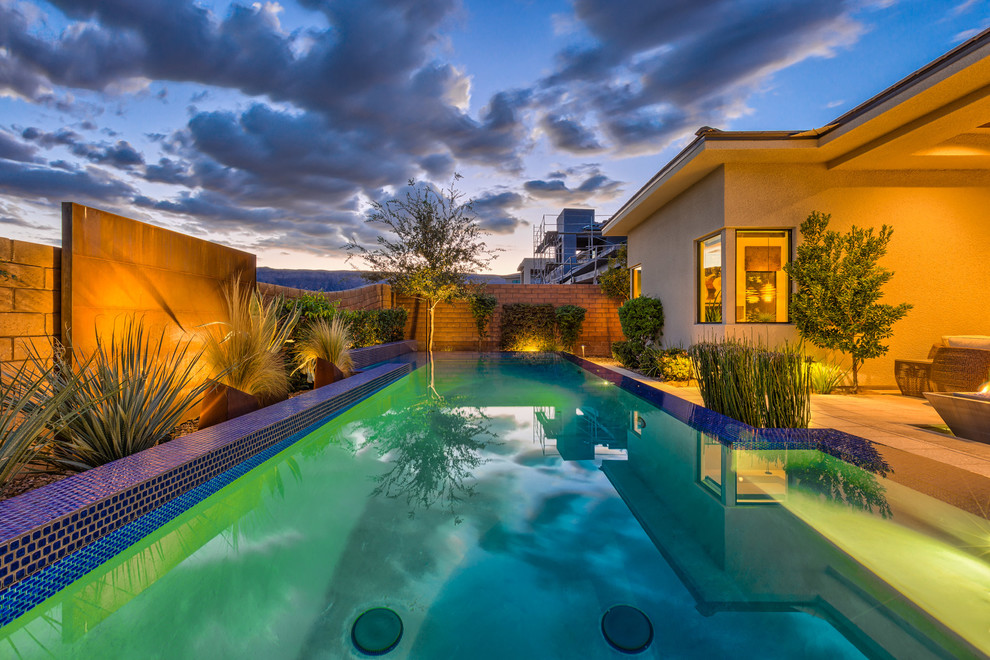 Foto de piscina infinita actual de tamaño medio rectangular en patio trasero con adoquines de hormigón