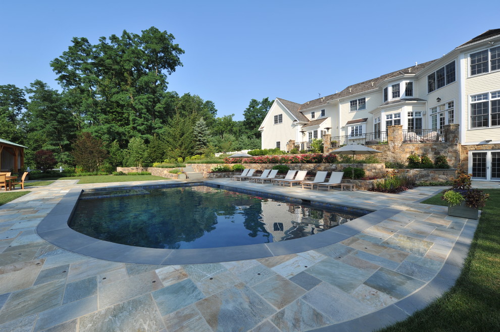 Immagine di una grande piscina monocorsia tradizionale rettangolare dietro casa con una dépendance a bordo piscina e piastrelle