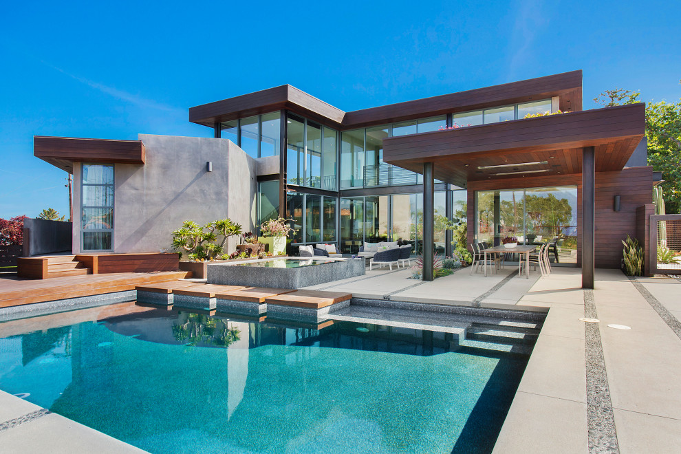 Diseño de piscina contemporánea de tamaño medio rectangular en patio trasero con losas de hormigón