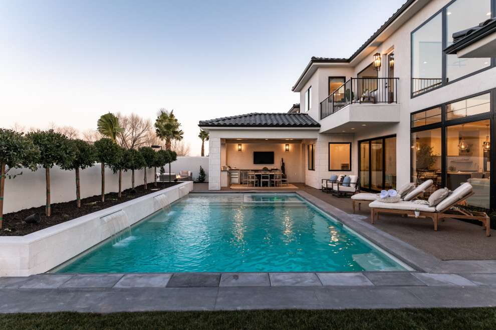 Immagine di una grande piscina monocorsia minimalista rettangolare dietro casa con una vasca idromassaggio e piastrelle