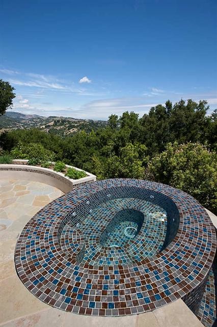 Cette photo montre une piscine à débordement et arrière méditerranéenne de taille moyenne et sur mesure avec des pavés en pierre naturelle et un bain bouillonnant.