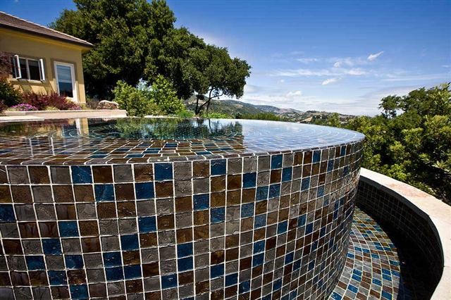 Inspiration for a medium sized mediterranean back custom shaped infinity hot tub in San Francisco with natural stone paving.
