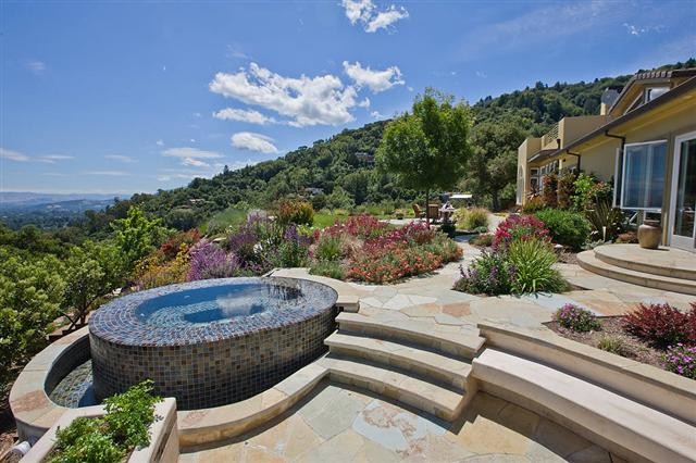 Ejemplo de piscinas y jacuzzis infinitos mediterráneos de tamaño medio a medida en patio trasero con adoquines de piedra natural