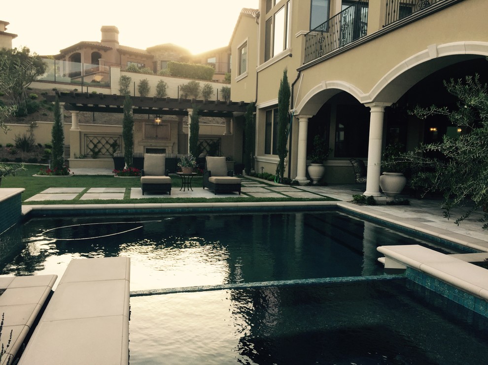 Example of a large backyard stone and custom-shaped pool fountain design in Los Angeles