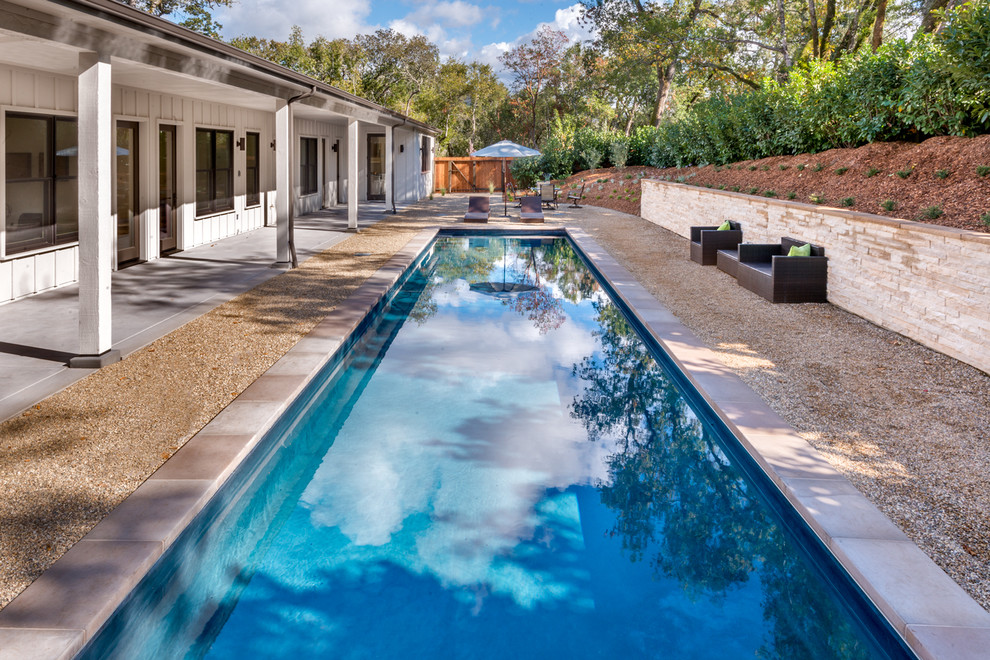 Diseño de piscina campestre rectangular en patio delantero con gravilla