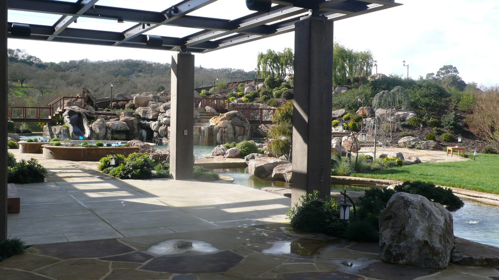 Идея дизайна: огромный естественный бассейн произвольной формы на заднем дворе в морском стиле с джакузи и покрытием из каменной брусчатки