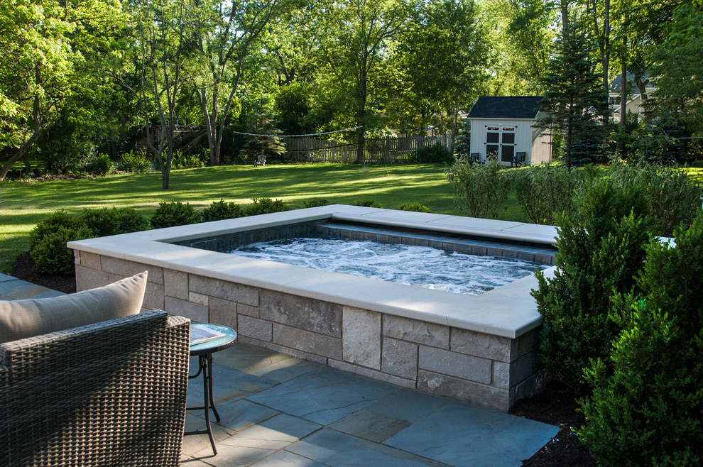 Design ideas for a small classic back rectangular natural hot tub in Chicago with a shelter and natural stone paving.