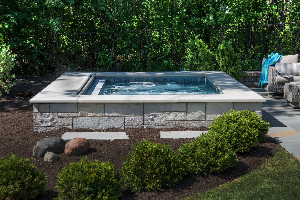 Esempio di una piccola piscina naturale chic rettangolare dietro casa con una vasca idromassaggio e pavimentazioni in pietra naturale