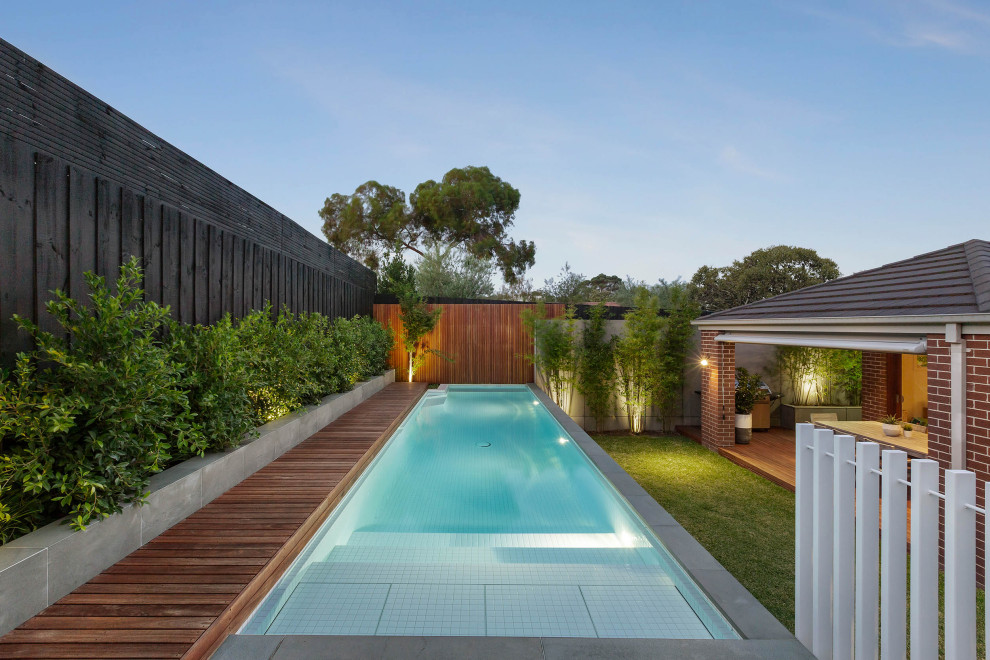 Cette image montre une piscine design rectangle avec une terrasse en bois.
