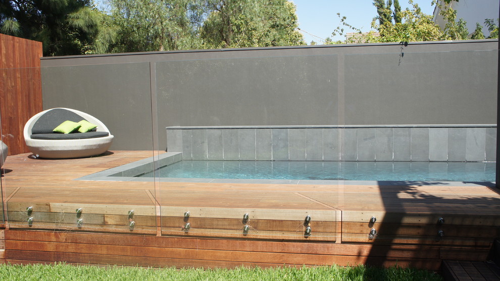 Example of a mid-sized trendy courtyard rectangular lap pool design in Melbourne with decking