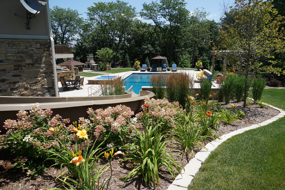 Imagen de piscina con tobogán alargada tradicional renovada grande rectangular en patio trasero con adoquines de hormigón