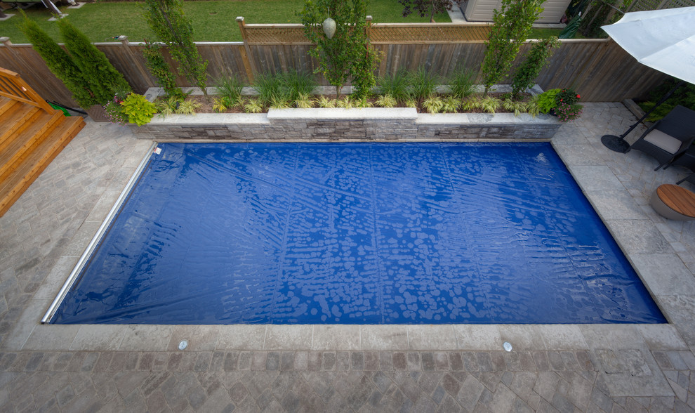 Diseño de piscina con fuente clásica de tamaño medio rectangular en patio trasero con adoquines de ladrillo
