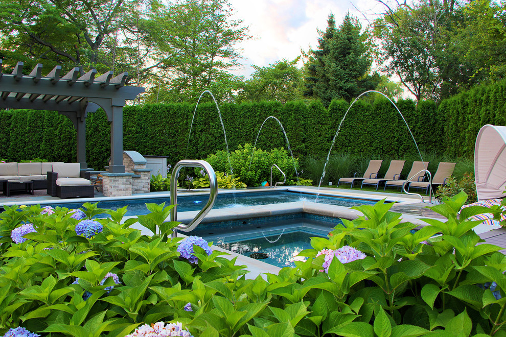 Cette photo montre une piscine arrière et naturelle chic rectangle avec des pavés en pierre naturelle et un bain bouillonnant.