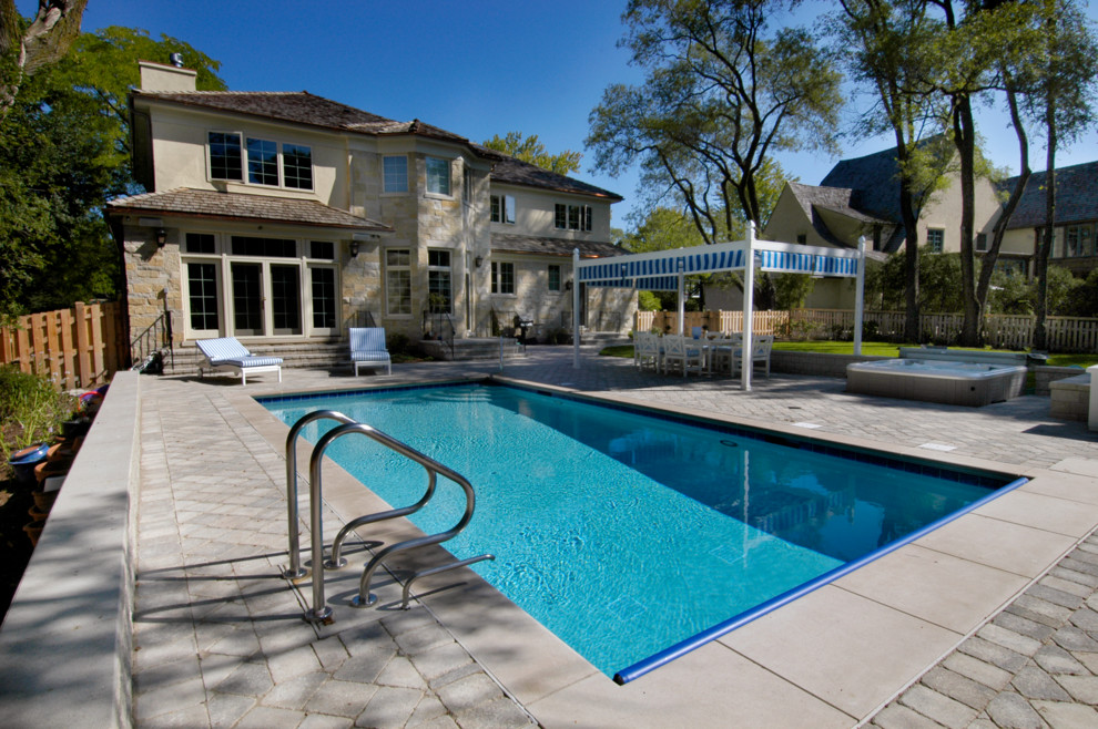 Foto de piscinas y jacuzzis alargados clásicos pequeños rectangulares en patio trasero con adoquines de hormigón
