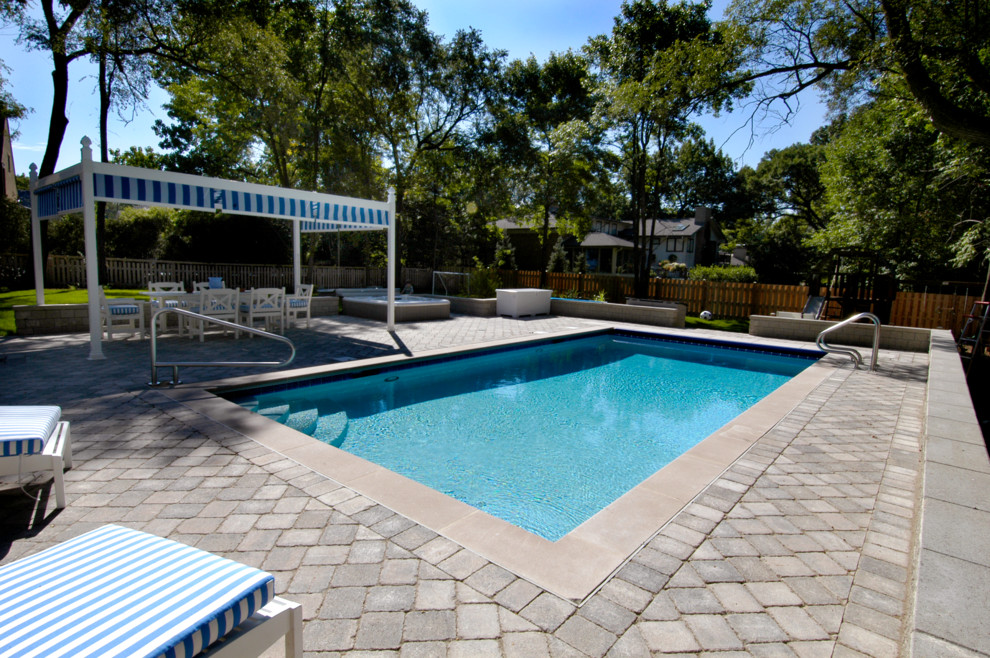 Example of a small classic backyard concrete paver and rectangular lap hot tub design in Chicago