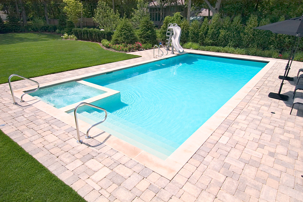 Ejemplo de piscina alargada clásica pequeña rectangular en patio trasero con adoquines de hormigón