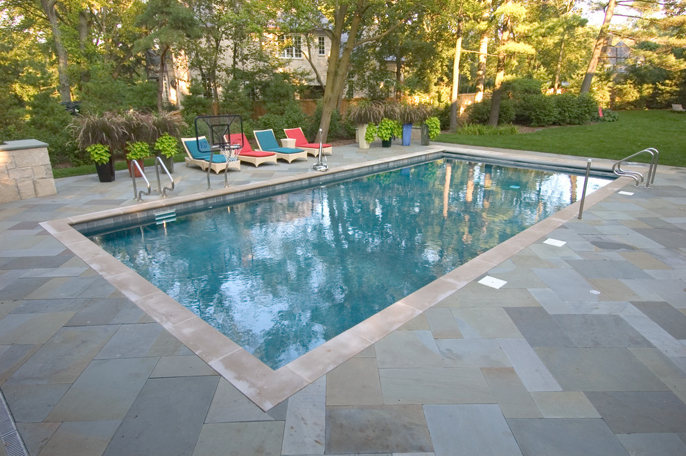 Imagen de piscina alargada tradicional de tamaño medio rectangular en patio trasero con adoquines de piedra natural
