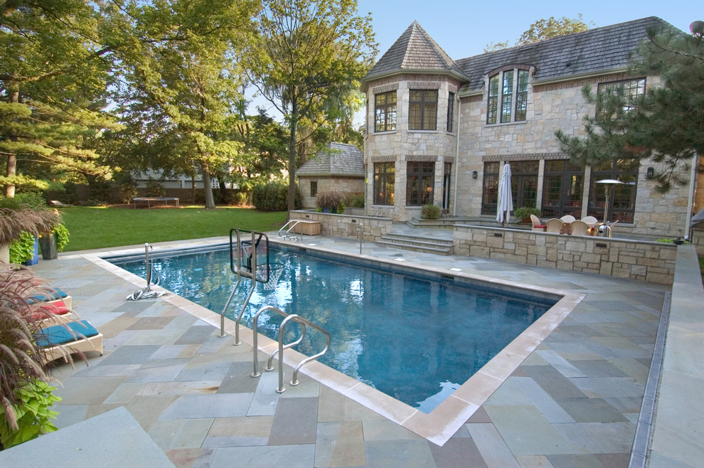 Ejemplo de piscina alargada tradicional de tamaño medio rectangular en patio trasero con adoquines de piedra natural