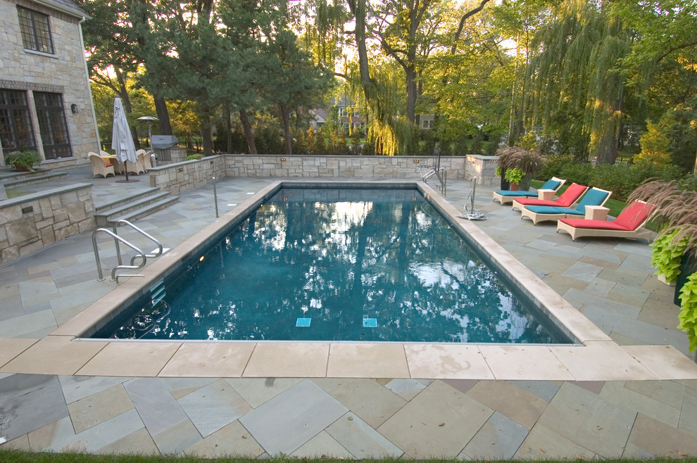 Diseño de piscina alargada tradicional de tamaño medio rectangular en patio trasero con adoquines de piedra natural
