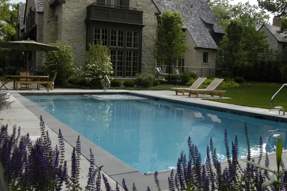Immagine di una piscina monocorsia classica rettangolare di medie dimensioni e dietro casa con una vasca idromassaggio e pavimentazioni in pietra naturale