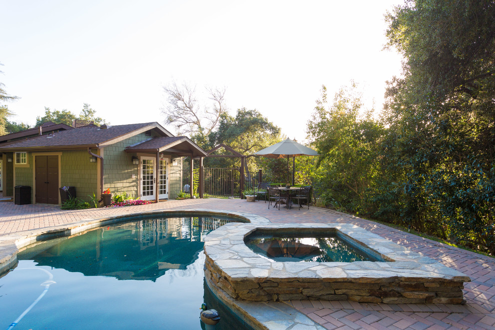 Immagine di una piscina monocorsia american style personalizzata dietro casa con una vasca idromassaggio e pavimentazioni in mattoni