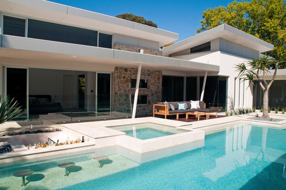 Inspiration för stora moderna anpassad pooler på baksidan av huset, med naturstensplattor