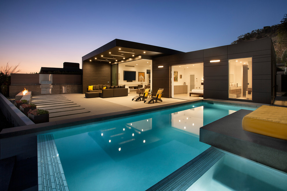 Ejemplo de piscinas y jacuzzis infinitos actuales de tamaño medio rectangulares en patio trasero con adoquines de hormigón