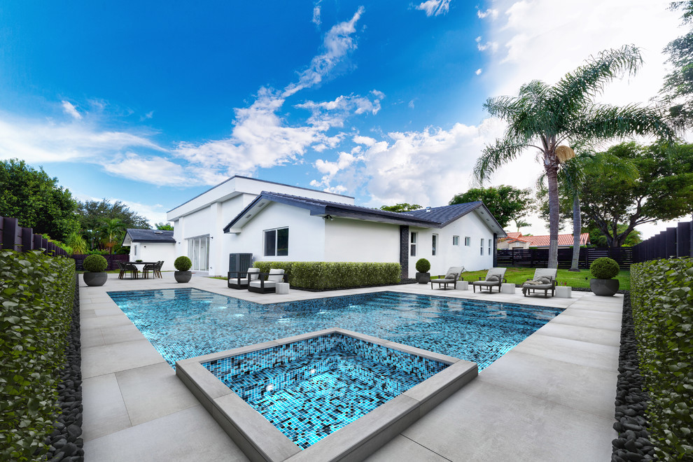 Diseño de piscinas y jacuzzis alargados contemporáneos grandes en forma de L en patio trasero con losas de hormigón