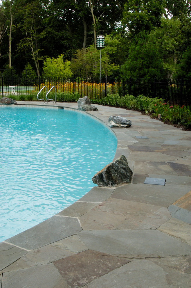 Modelo de piscinas y jacuzzis naturales rústicos grandes en patio trasero con adoquines de piedra natural