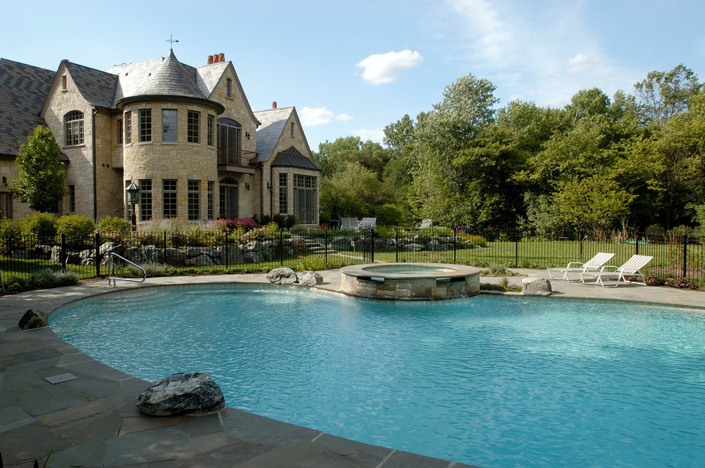 На фото: большой естественный бассейн на заднем дворе в стиле рустика с джакузи и покрытием из каменной брусчатки с