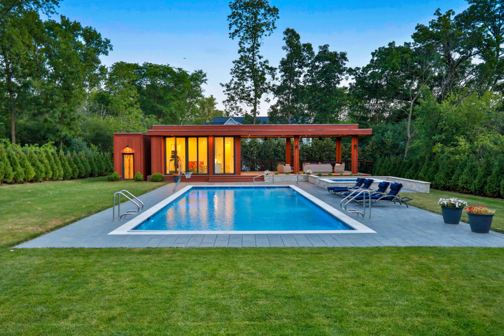 Foto de piscinas y jacuzzis alargados clásicos de tamaño medio rectangulares en patio trasero con adoquines de hormigón