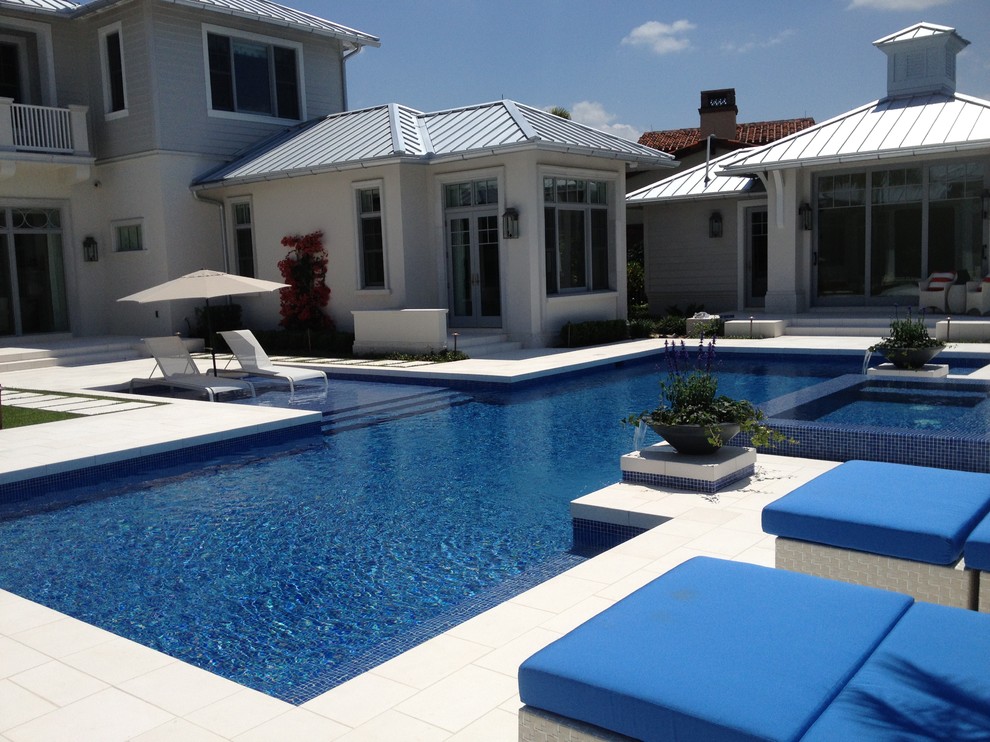 Ejemplo de piscinas y jacuzzis costeros grandes rectangulares en patio trasero con adoquines de piedra natural