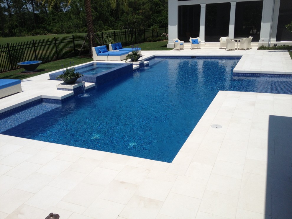 Ispirazione per una grande piscina costiera rettangolare dietro casa con pavimentazioni in pietra naturale e una vasca idromassaggio