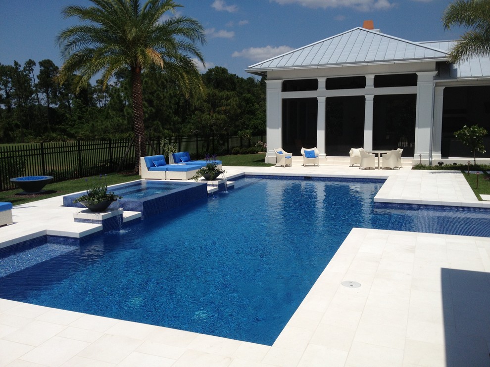 Ispirazione per una grande piscina stile marinaro rettangolare dietro casa con pavimentazioni in pietra naturale e una vasca idromassaggio