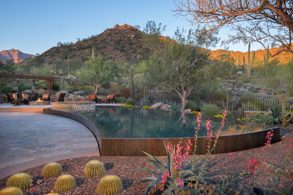 Imagen de piscina infinita de estilo americano grande a medida en patio trasero con adoquines de piedra natural