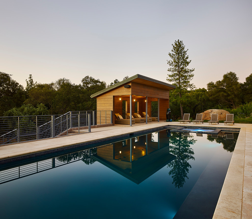 Esempio di una grande piscina monocorsia design rettangolare dietro casa con una vasca idromassaggio e piastrelle
