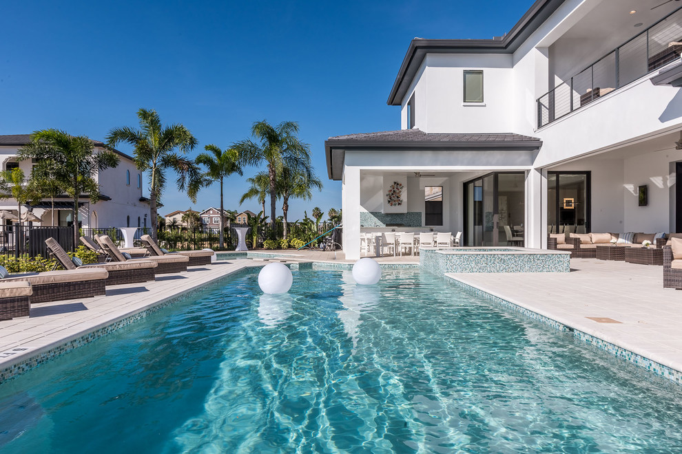 Immagine di una grande piscina monocorsia design personalizzata dietro casa con una vasca idromassaggio e pavimentazioni in pietra naturale