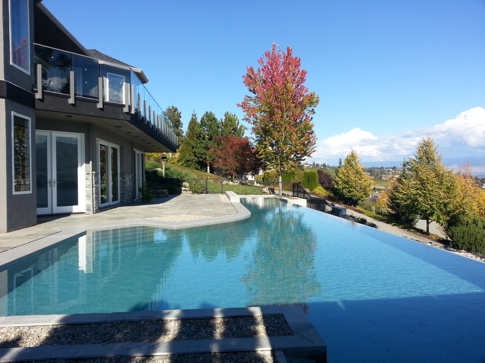Ejemplo de piscina alargada moderna grande en forma de L en patio delantero con suelo de baldosas