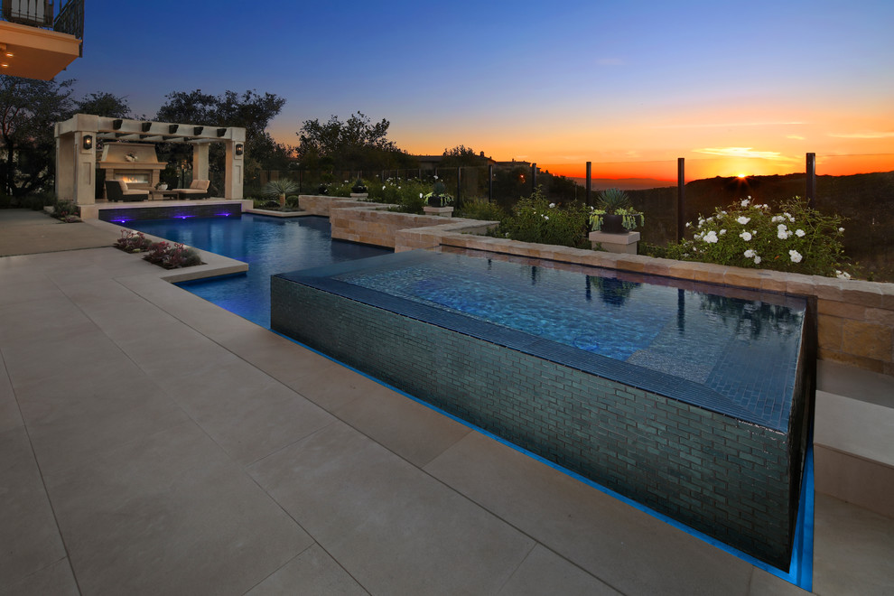 Imagen de piscinas y jacuzzis infinitos contemporáneos grandes a medida en patio trasero con suelo de baldosas