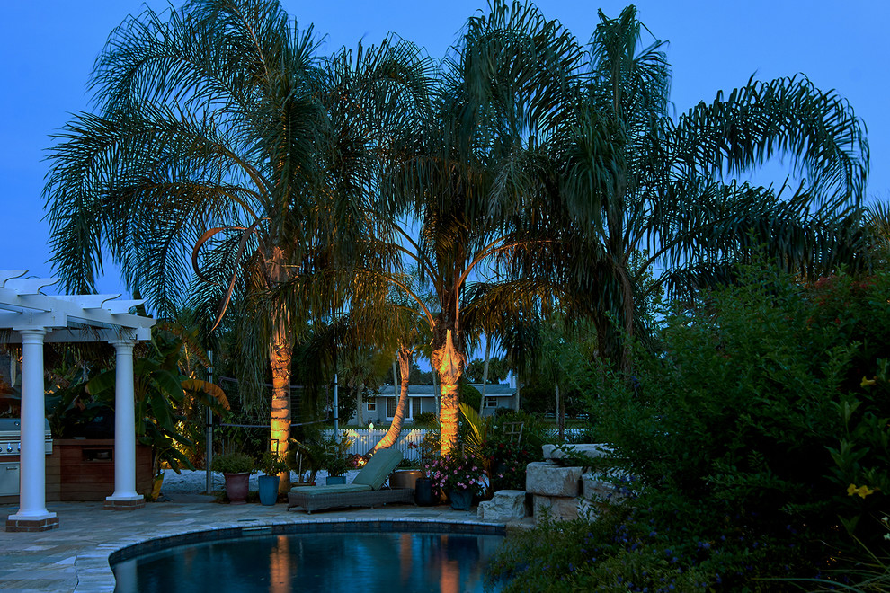Diseño de piscina exótica de tamaño medio a medida en patio trasero con adoquines de piedra natural