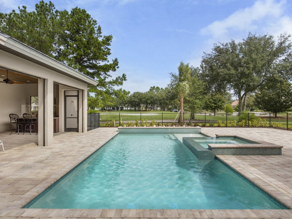 Esempio di una piscina monocorsia tradizionale rettangolare di medie dimensioni e dietro casa con una vasca idromassaggio e pavimentazioni in pietra naturale