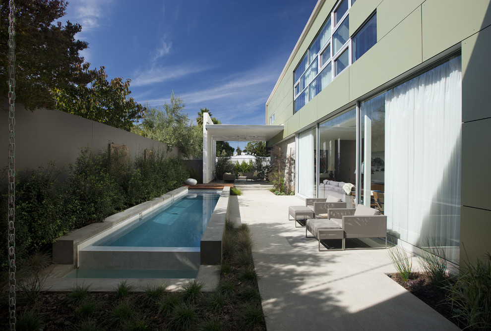 Immagine di una piccola piscina monocorsia minimalista rettangolare nel cortile laterale con lastre di cemento